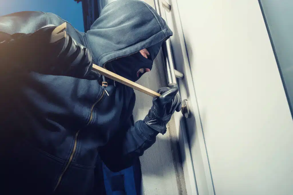 Schlüsseldienst Unterhaching - a person in a mask and gloves breaking a door